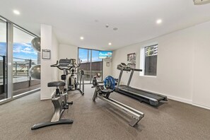 Une salle de sport équipée de machines de cardio, d’un tapis de course et d’un banc de musculation.