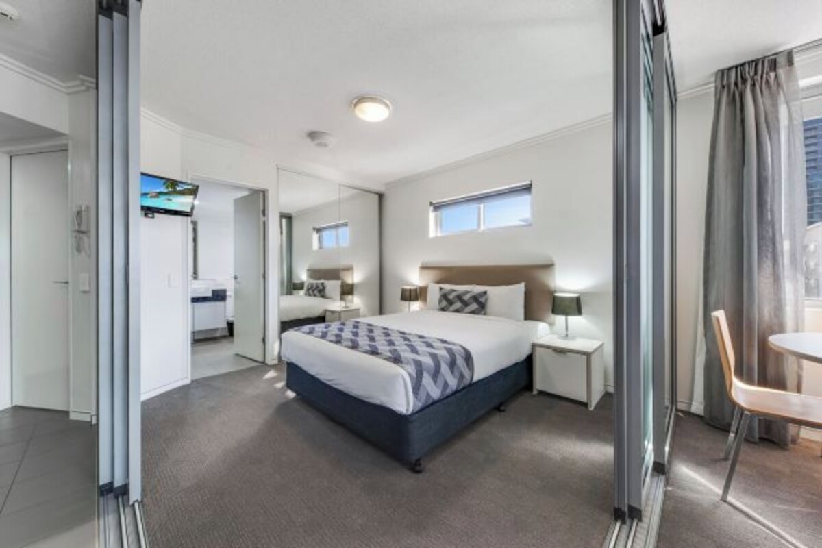 A modern hotel room with a large bed, bedside tables, a desk, and a chair.