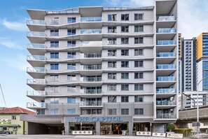 Un hôtel à plusieurs étages doté de balcons, une enseigne indiquant « The Capitol », et une architecture moderne.