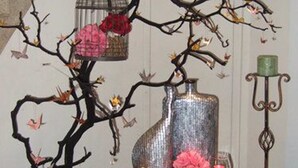 A table with a red tablecloth, a decorative tree with branches, a birdcage, and a vase with flowers. - Ximen Citizen Hotel (Taipei)