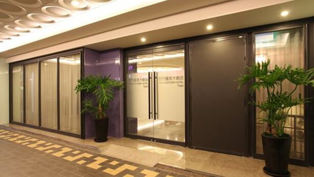A modern hotel lobby with a patterned floor, glass doors, and potted plants. - Ximen Citizen Hotel (Taipei)