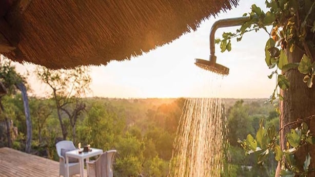 A wooden deck with a hot tub, a table with chairs, and a showerhead with water flowing. - Leopard Hills (Bushbuckridge)