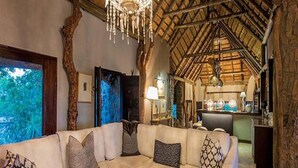 A spacious living room with a large white sofa, a wooden coffee table, and a chandelier. - Leopard Hills (Bushbuckridge)