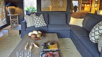 A modern living room with a grey sofa, patterned cushions, a coffee table with books and decorative items, and a map on the wall.
