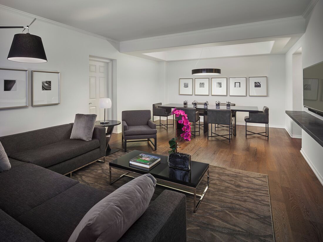 A modern living room with a sofa, coffee table, and a dining area with chairs and a table.