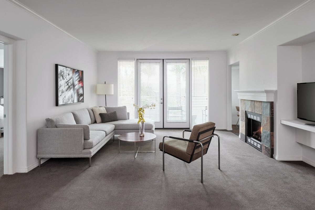 A modern living room with a grey sofa, a coffee table, a chair, and a fireplace.