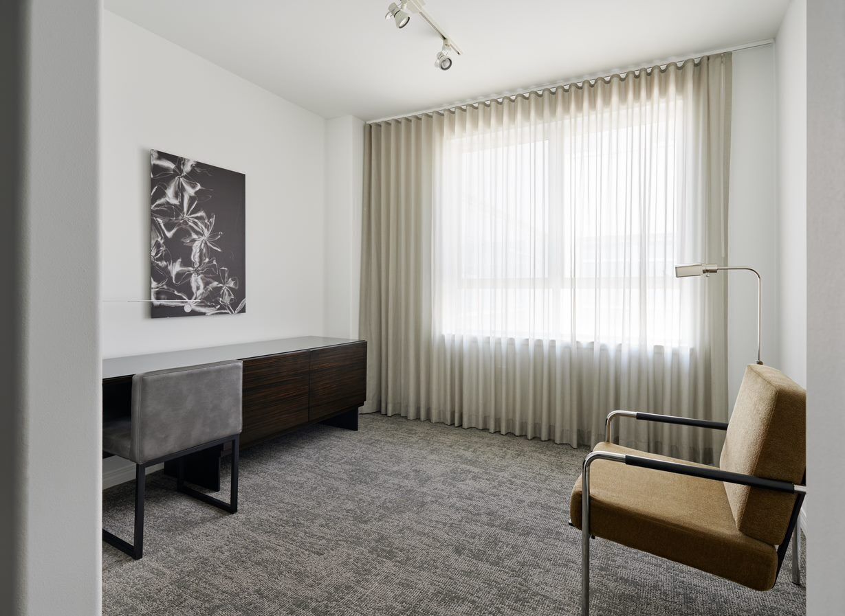 Una habitación moderna con escritorio, silla y una obra de arte en la pared.