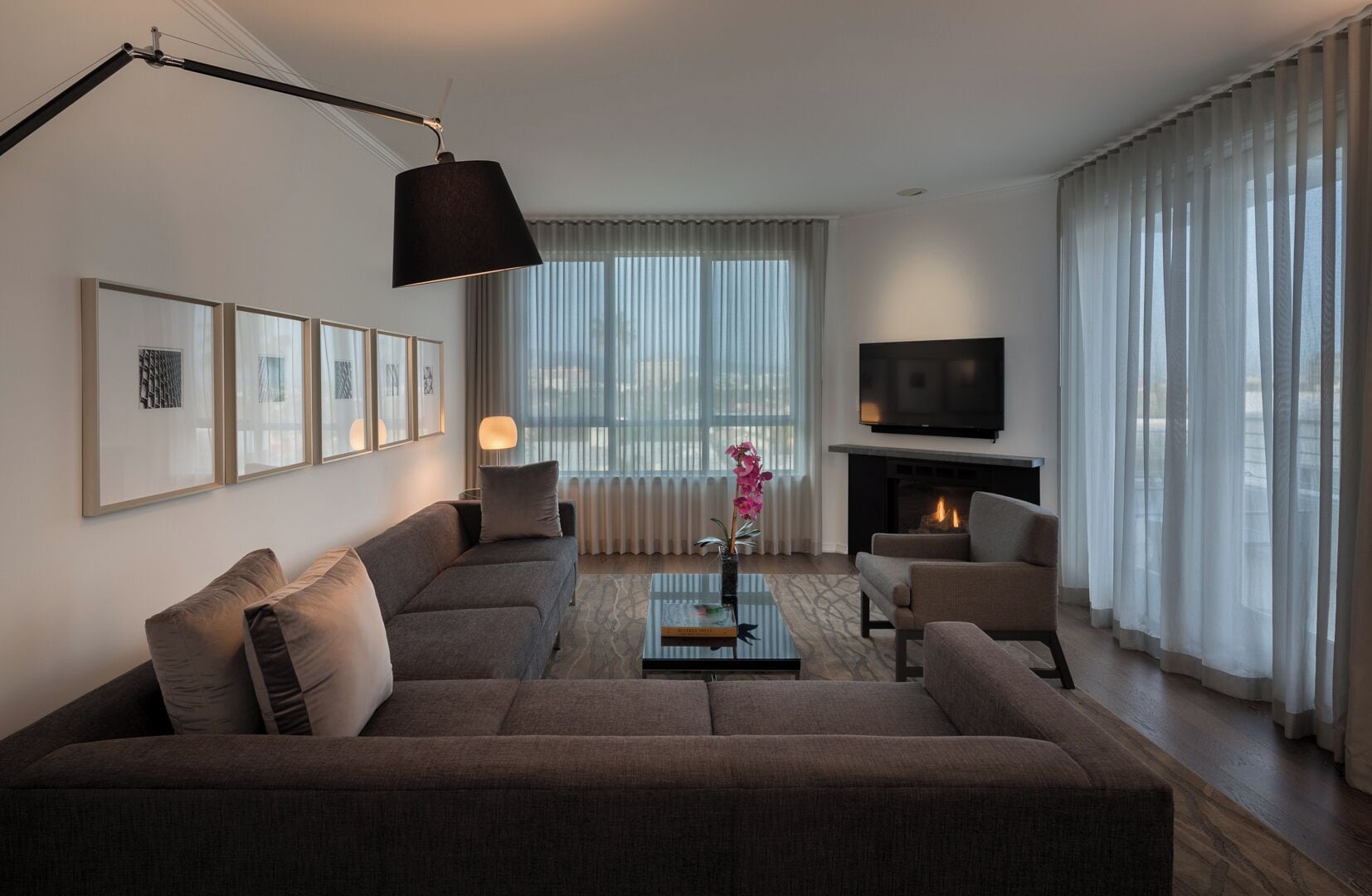 Un salon moderne avec un canapé, des fauteuils, une table basse, un téléviseur et une cheminée.
