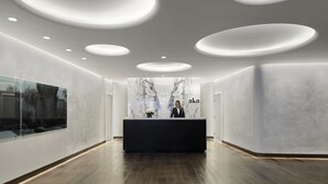 Un espace d’accueil moderne avec un mur en marbre, un(e) réceptionniste et une grande fenêtre.