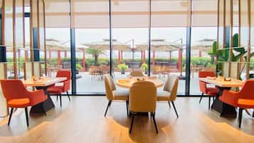 Un comedor moderno con grandes ventanales, suelo de madera y sillas color naranja.