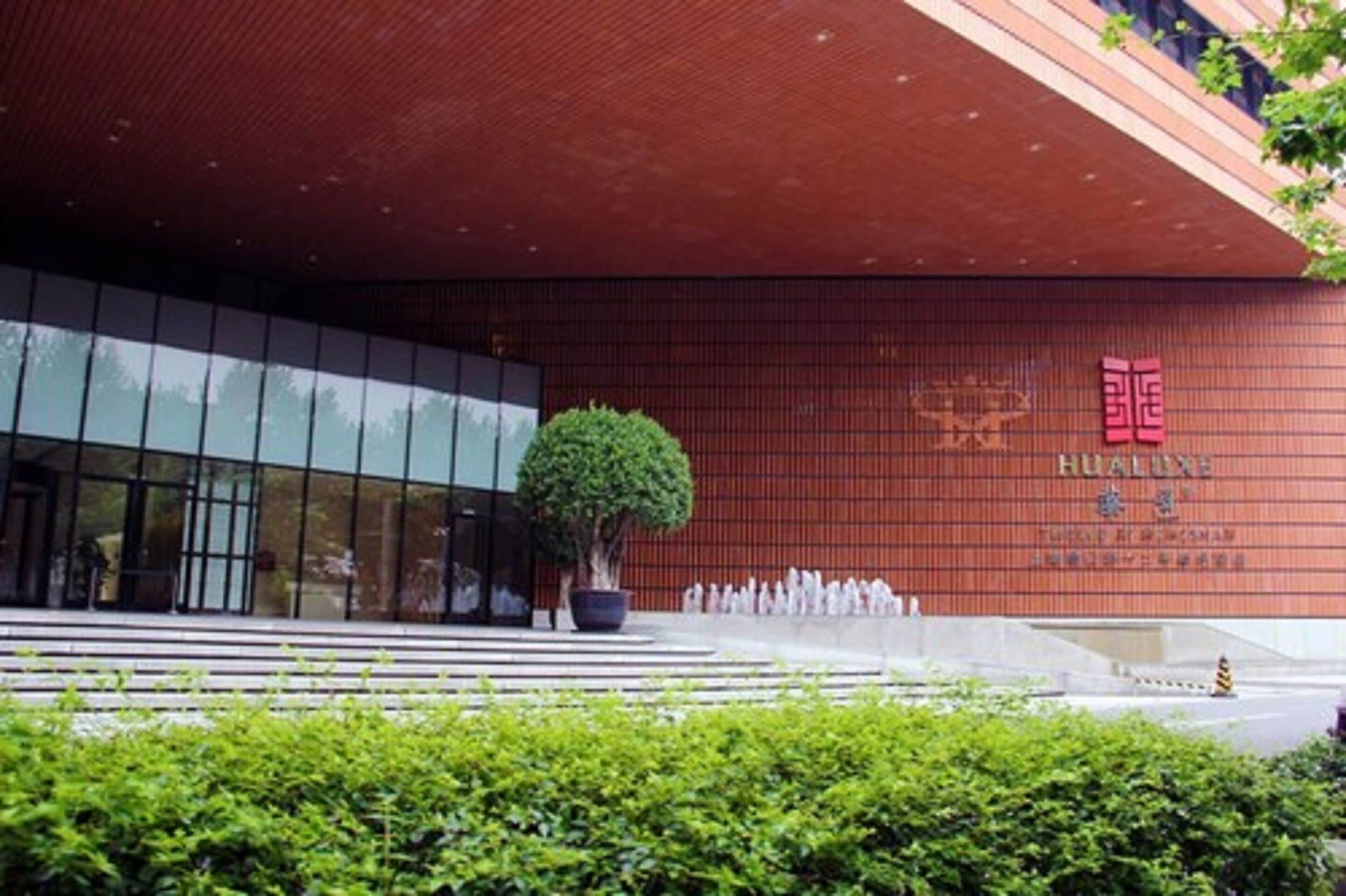 Ein modernes Gebäude mit roter Fassade und einem großen Baum davor.