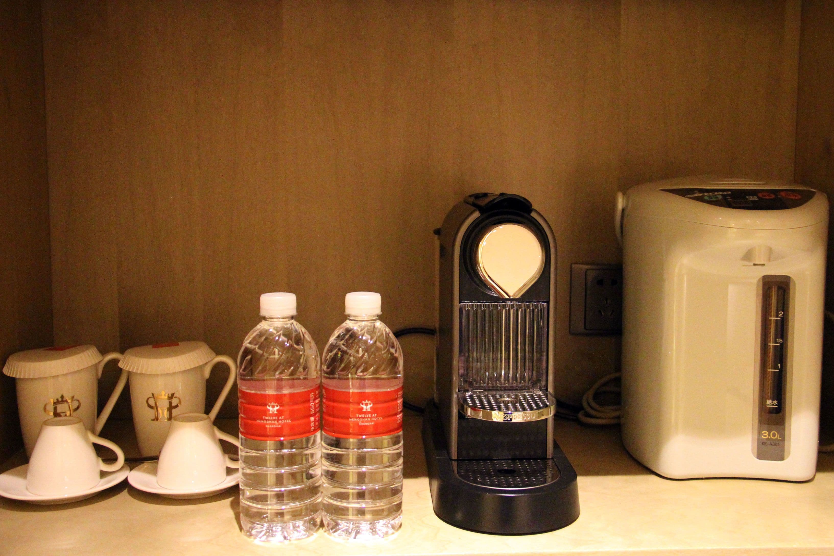 Une petite cuisine équipée d’une machine à café, de deux bouteilles d’eau et de deux théières.