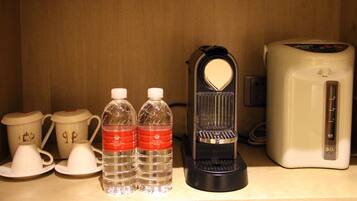 Une petite cuisine équipée d’une machine à café, de deux bouteilles d’eau et de deux théières.