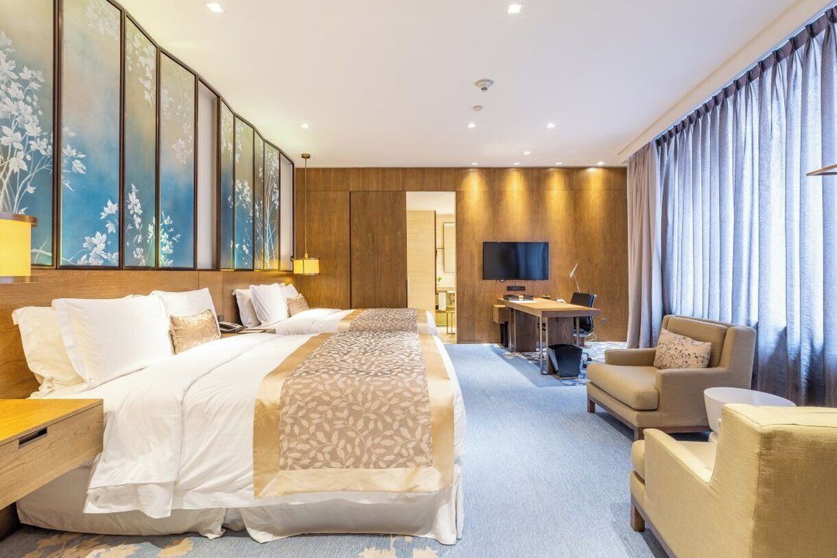 A hotel room with a large bed, a desk, a TV, and a seating area.