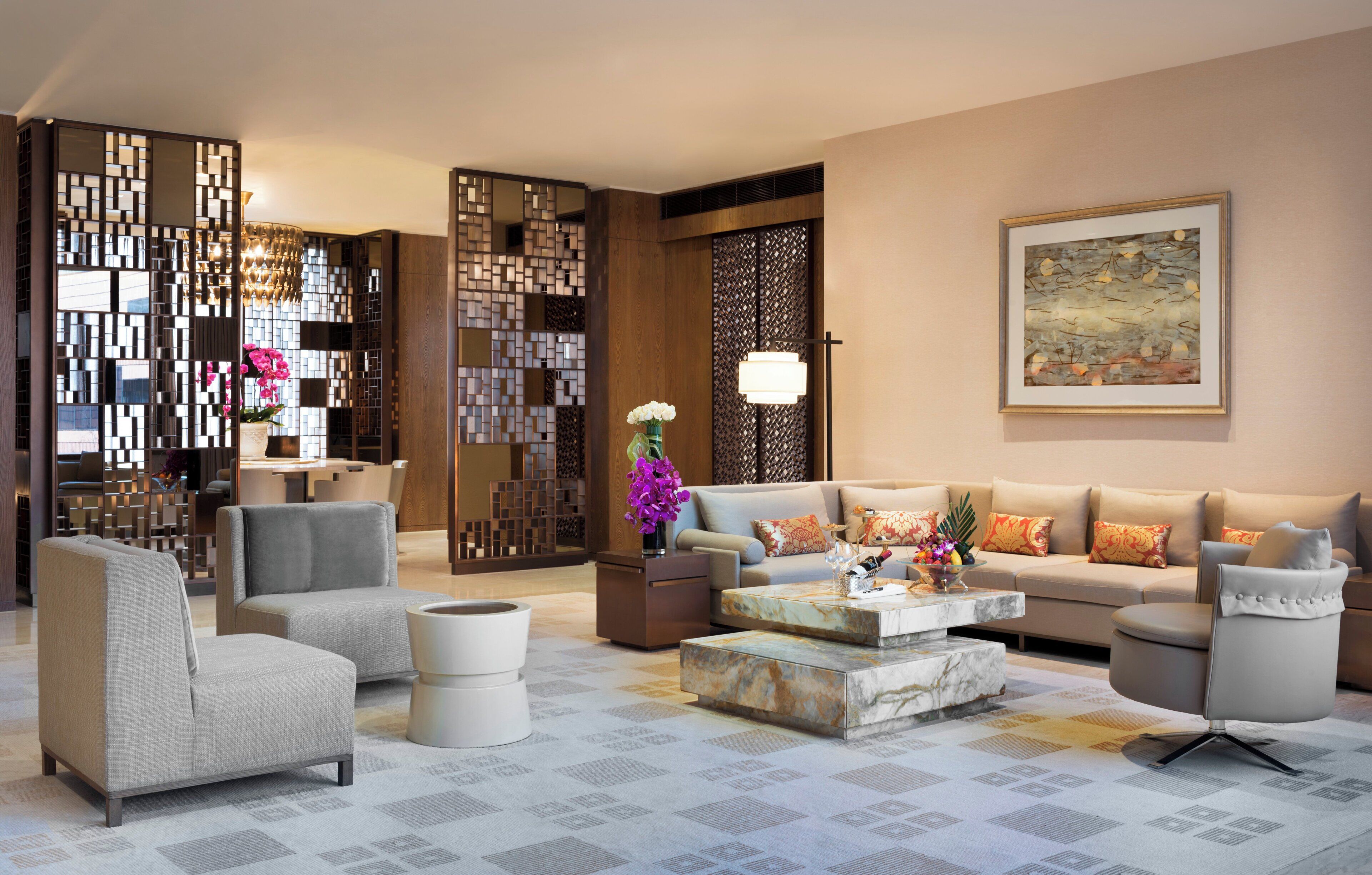 Una sala moderna con un sofá modular, sillones, una mesa de centro y un separador decorativo.