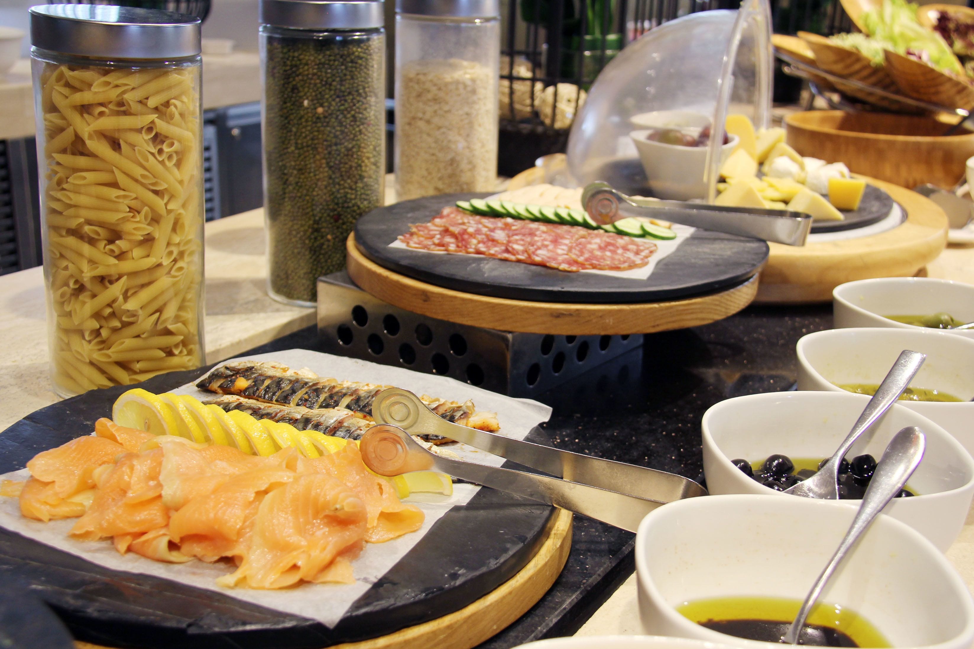 A buffet with various food items including pasta, smoked salmon, and cheese.