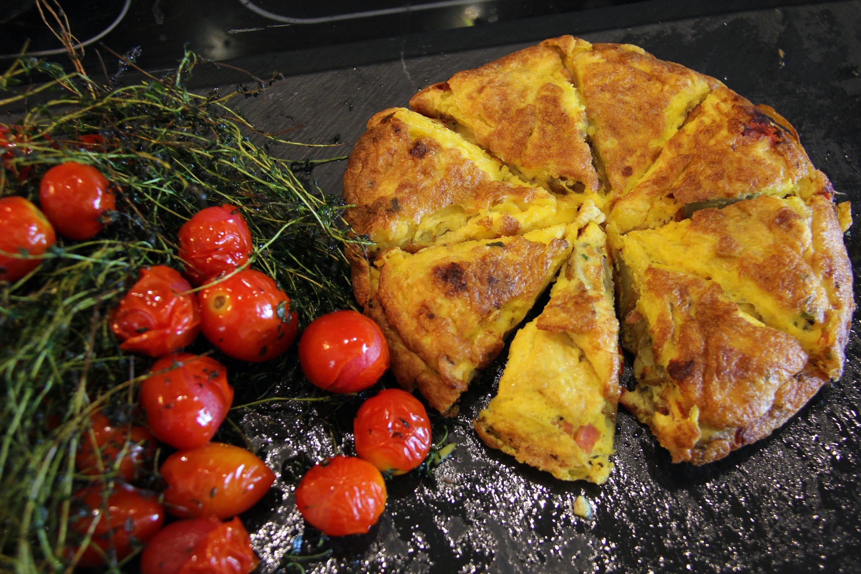 A quiche with a golden-brown crust, garnished with cherry tomatoes and herbs.