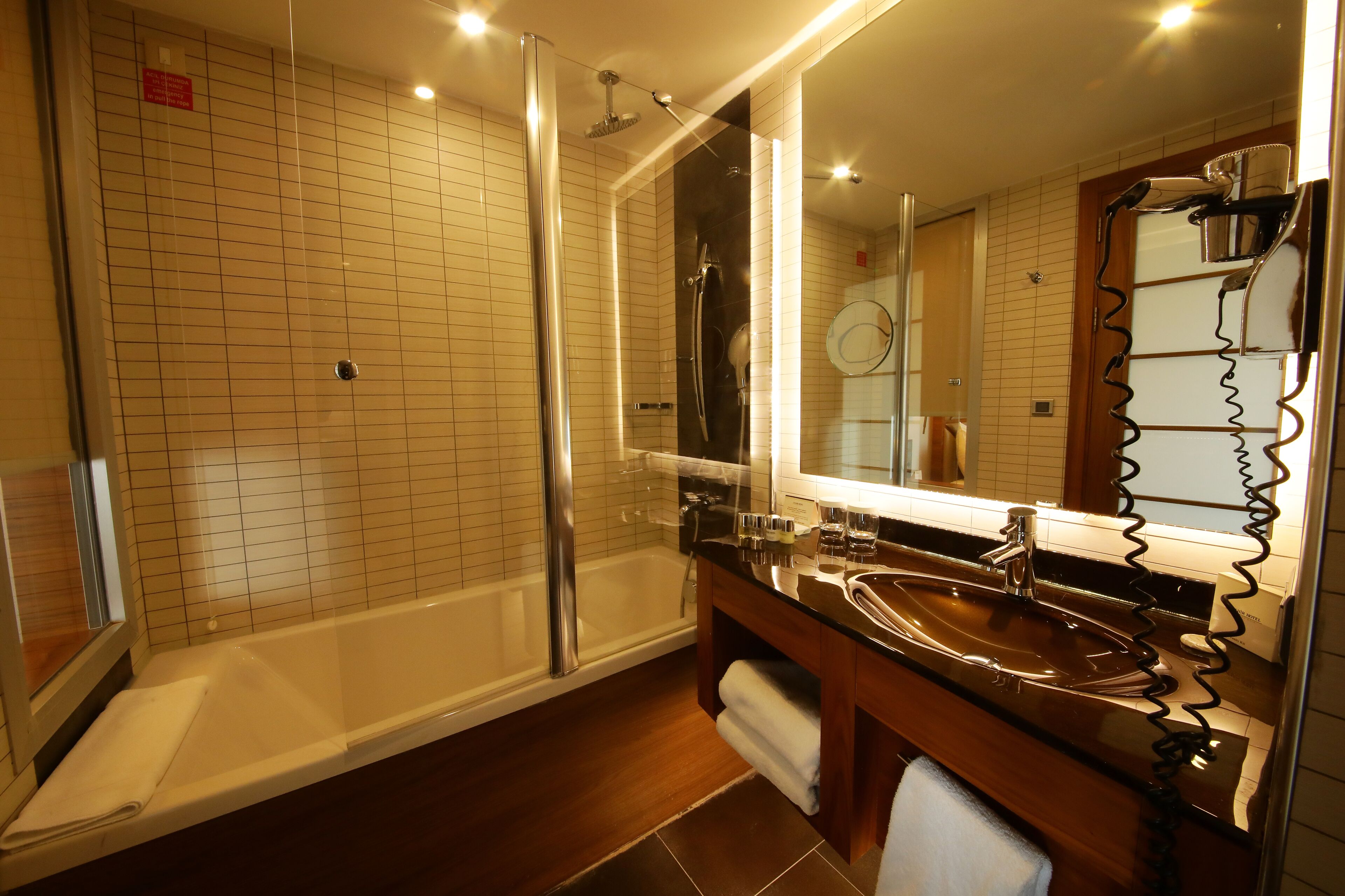 Une salle de bain moderne avec une douche à parois de verre, un grand miroir et un meuble-lavabo en bois.