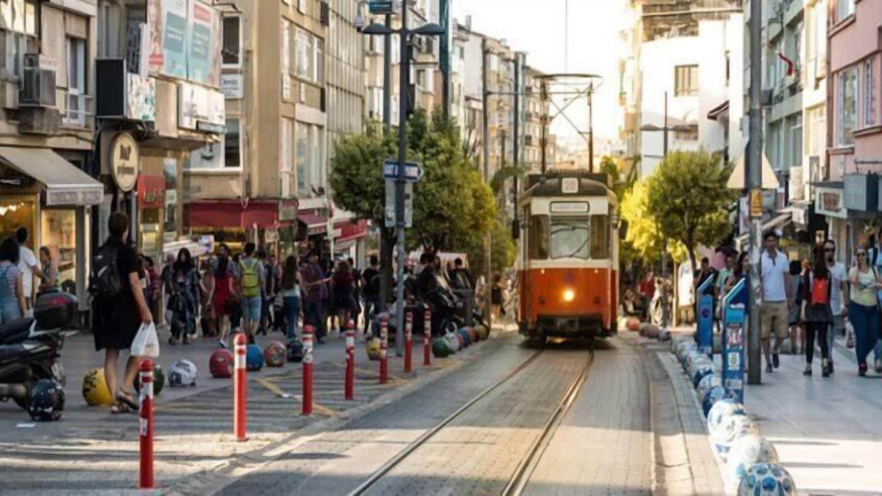 A tram moving through a busy urban street with pedestrians and shops.