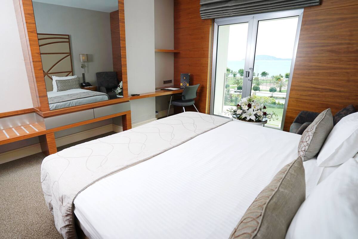 A modern hotel room with a bed, a desk, and a chair.
