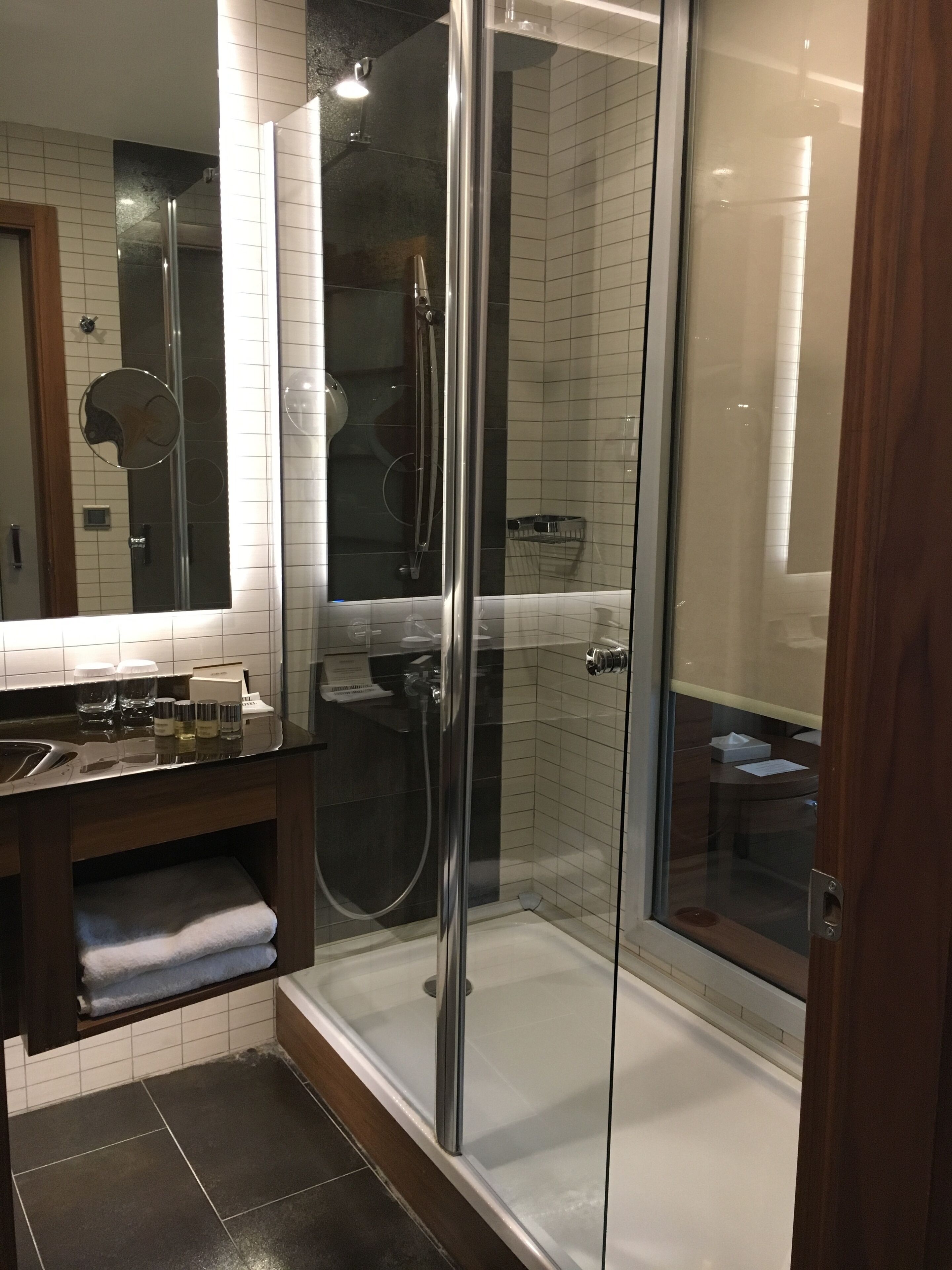 Une salle de bain moderne avec une douche à parois de verre, un meuble-lavabo avec un miroir et un porte-serviettes.