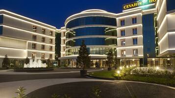 A modern hotel with a circular central courtyard, a fountain, and a clock tower.