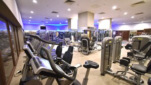 A gym with various exercise machines, including treadmills and weight stations, arranged in a spacious layout.