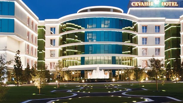A modern hotel with a central fountain, multiple floors, and a well-lit facade.