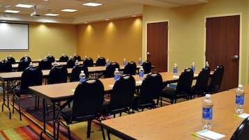 Un salón de conferencias con varias mesas y sillas, equipado con botellas de agua y tarjetas de nombres.