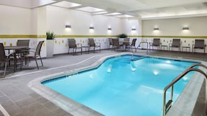Ein überdachter, innenliegender Swimmingpool mit gefliestem Deck und Liegestühlen.