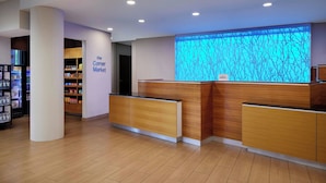 Ein Empfangsschalter, an der Wand ein blaues Baumotiv, ein Schild für den Kiosk und ein Verkaufsautomat.