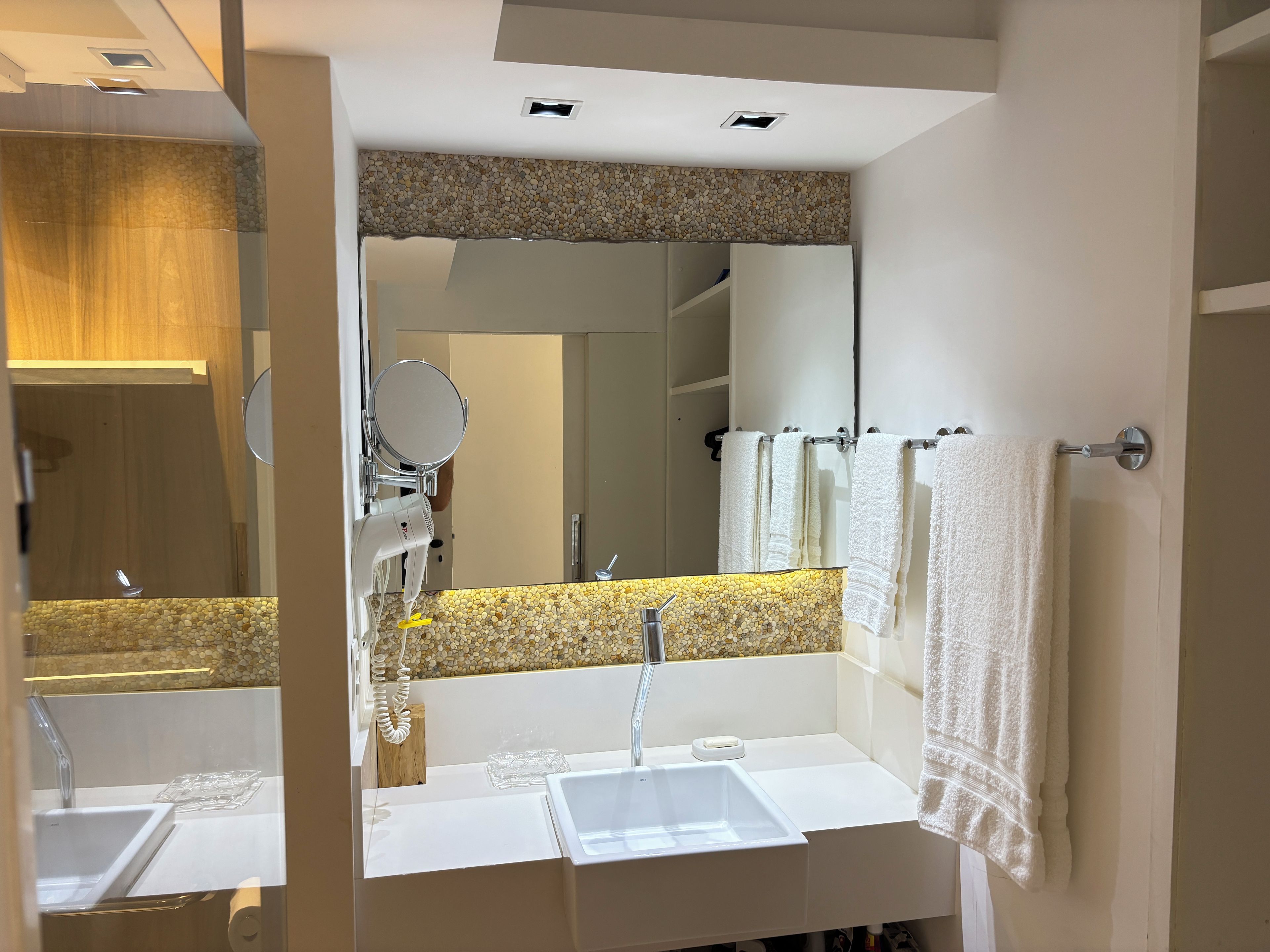 A bathroom with a white sink, a mirror, and a towel rack.