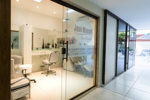 A modern hair salon interior with a glass door, a salon chair, and a counter with various hair products. - Mc Flats Ipanema Beach Star (Rio de Janeiro)