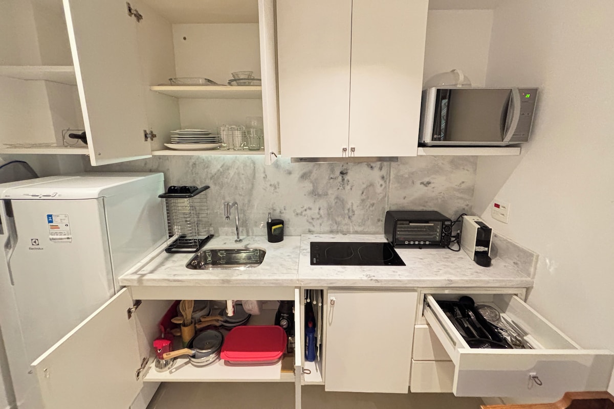 Una cucina compatta con forno a microonde, tostapane e lavandino.