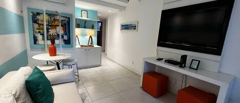 Un salon moderne avec un canapé, un téléviseur et un petit coin repas.