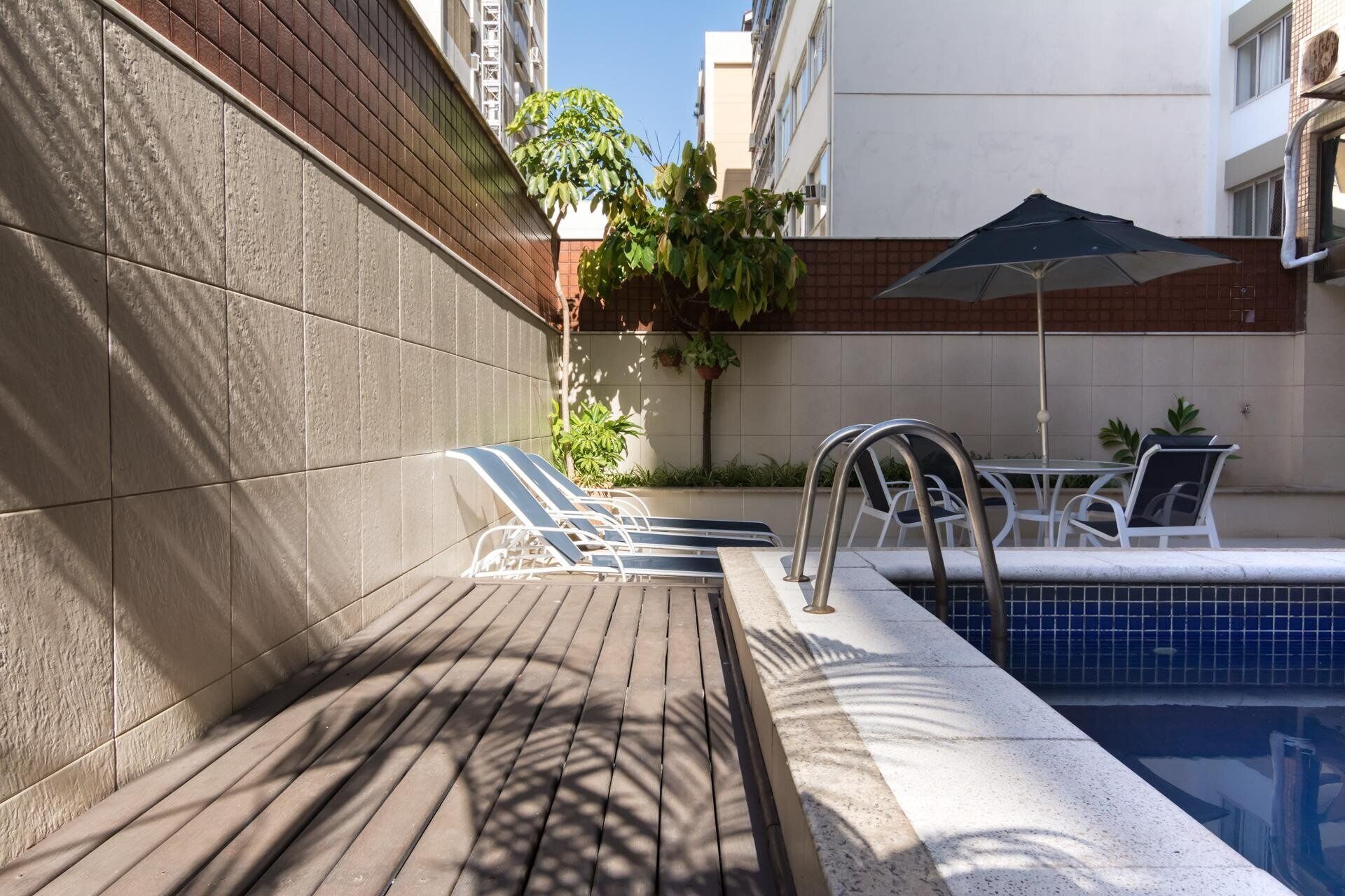 A poolside area with lounge chairs, a pool, and a table with chairs.