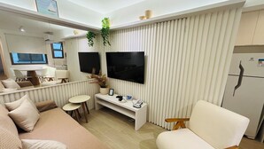 A modern living room with a sofa, a coffee table, a TV, and a refrigerator. - Mc Flats Ipanema Beach Star (Rio de Janeiro)