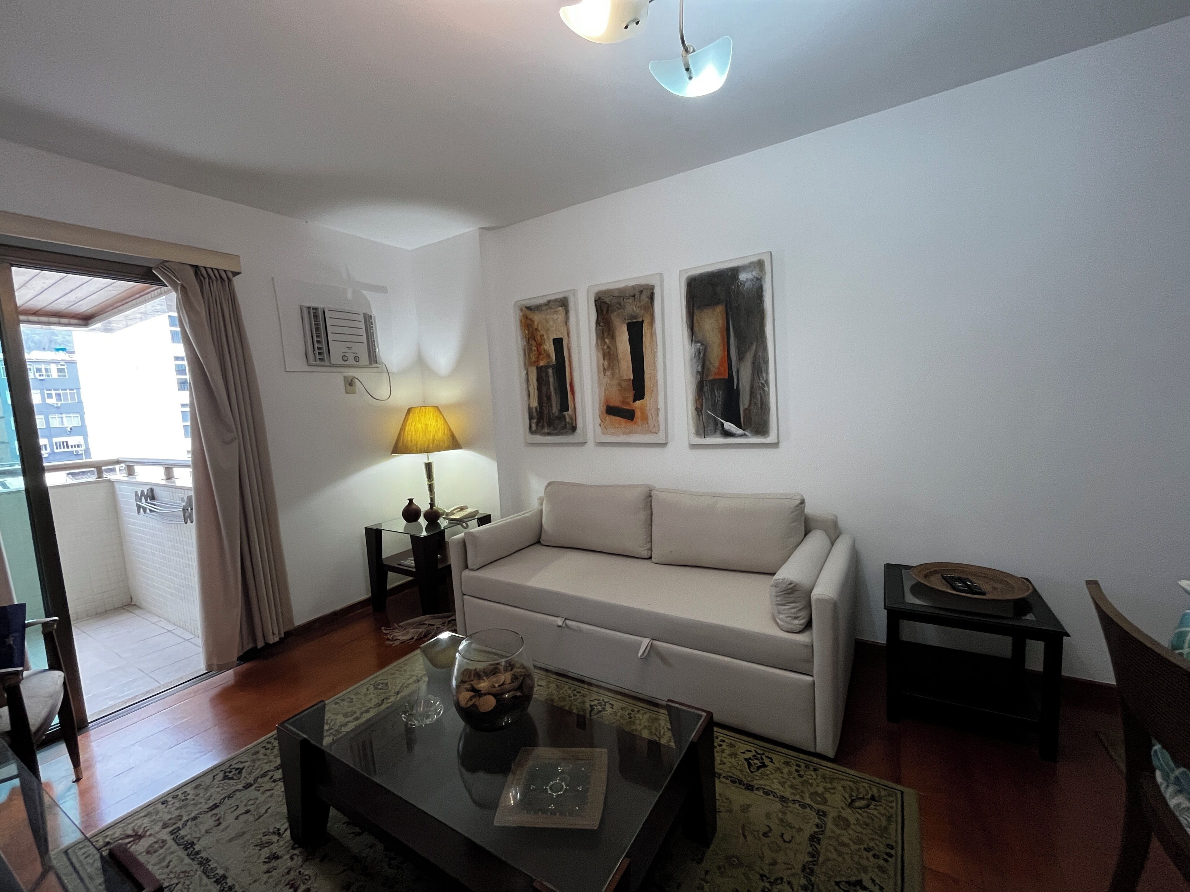 A living room with a sofa, a coffee table, a lamp, and abstract art on the wall.