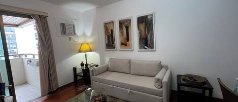 Una sala de estar con sofá, mesa de centro, lámpara y arte abstracto en la pared.