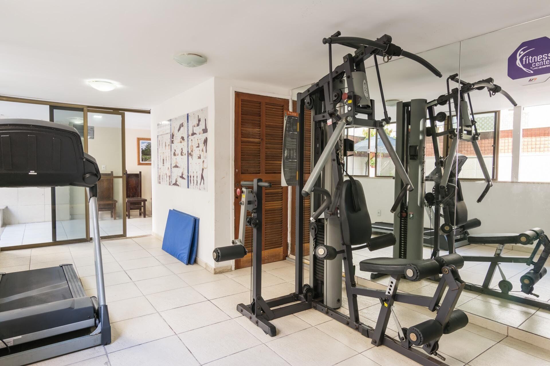 A fitness center with a treadmill, weight machines, and exercise mats.