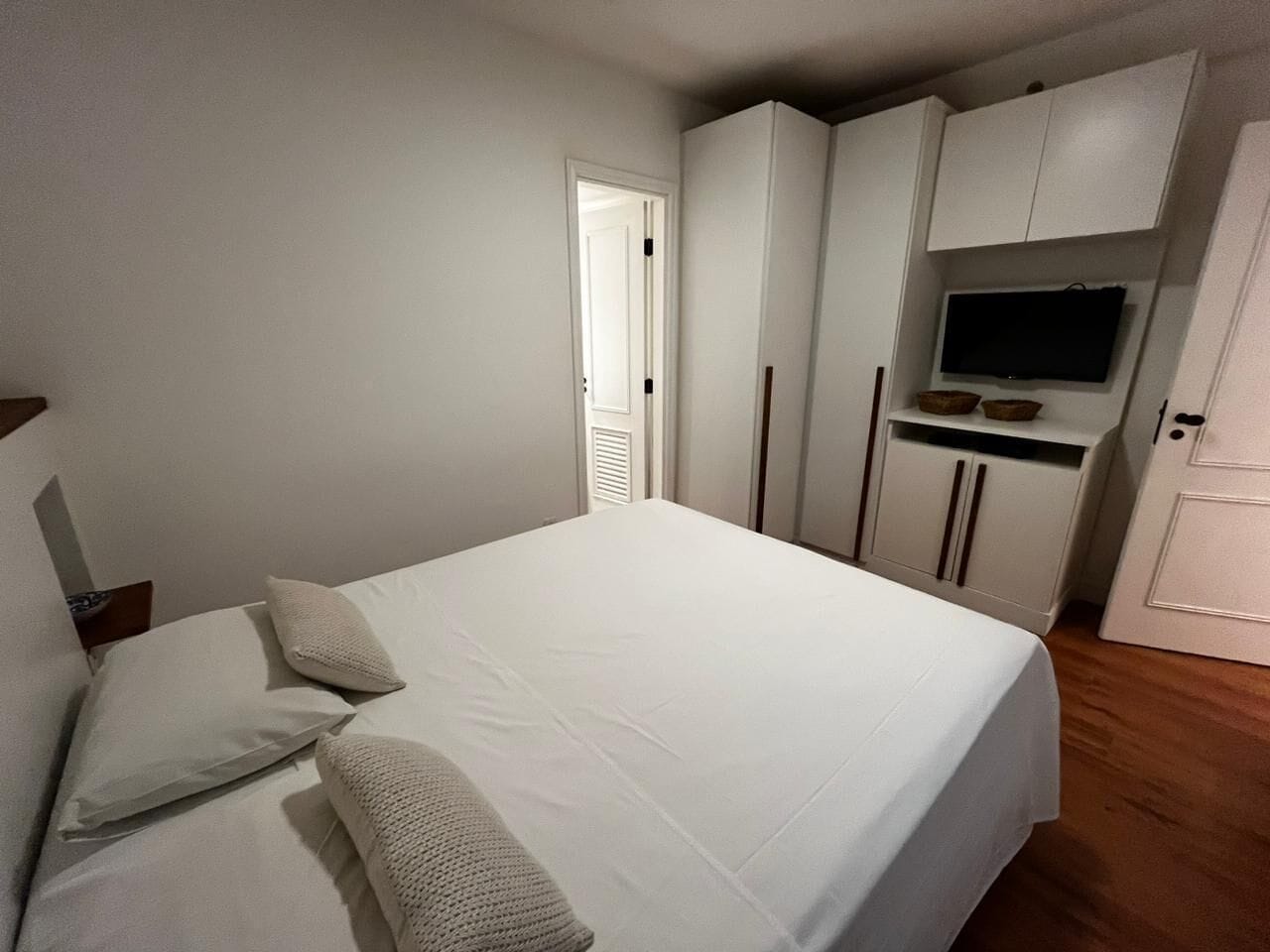 Une chambre à coucher avec un lit, des oreillers, une armoire et un téléviseur.