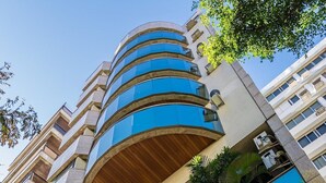 A modern building with a curved facade, large windows, and a sign reading "PANENA Beach Tower". - Mc Flats Ipanema Beach Star (Rio de Janeiro)