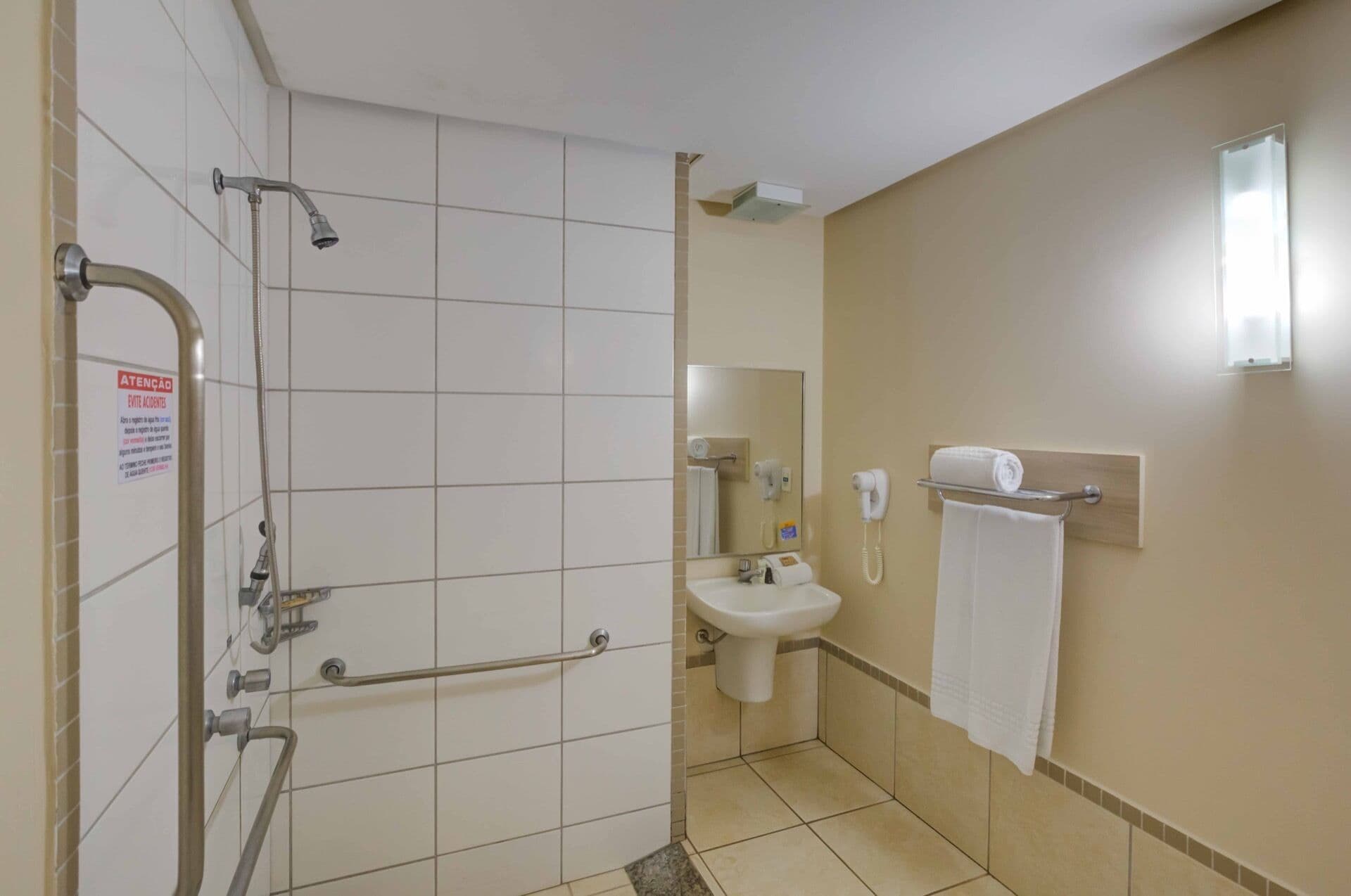A bathroom with a shower, a sink, a towel rack, and a hand dryer.