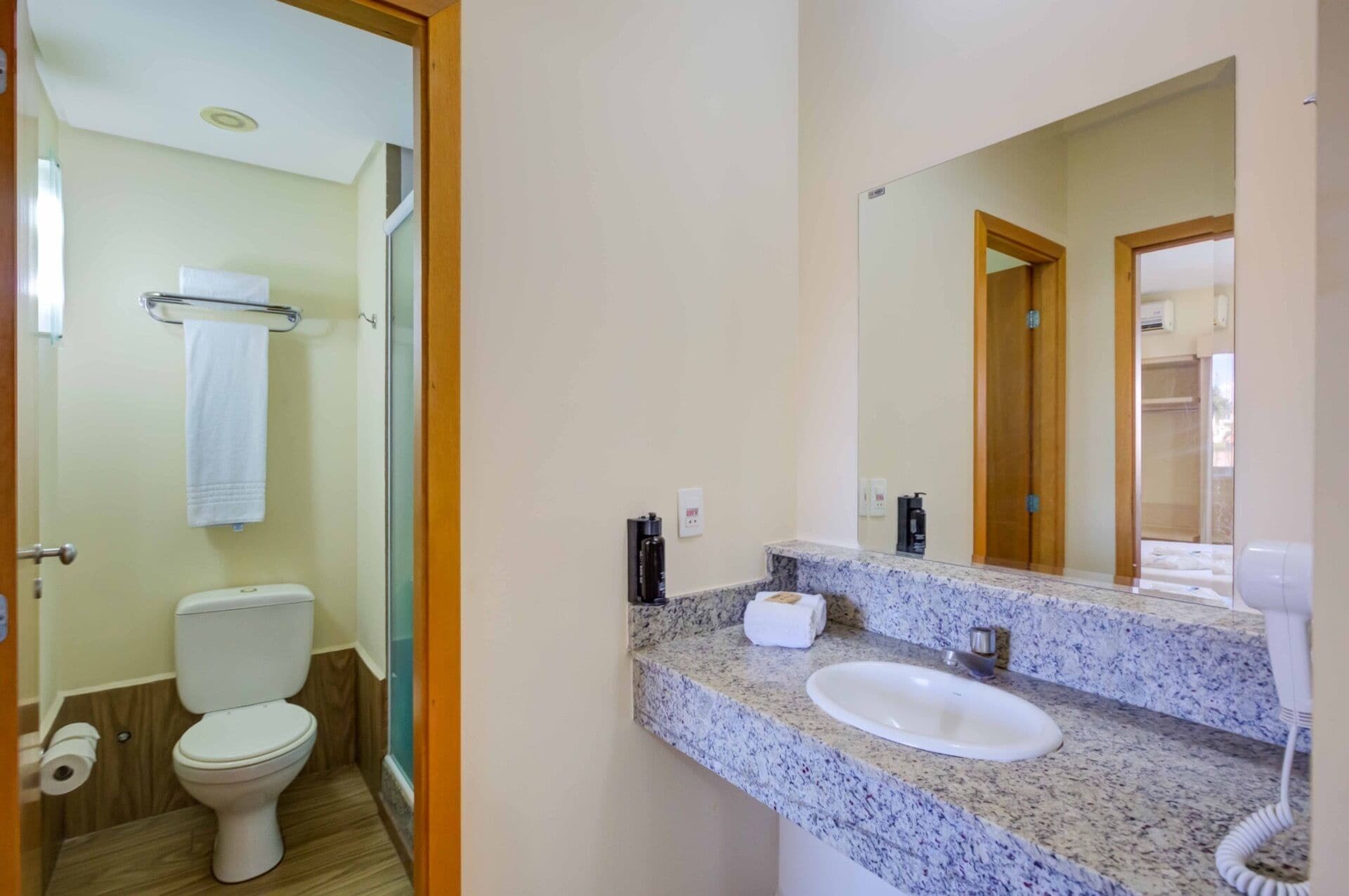 Une salle de bain équipée de toilettes, d’un lavabo, d’un miroir et d’un porte-serviettes.