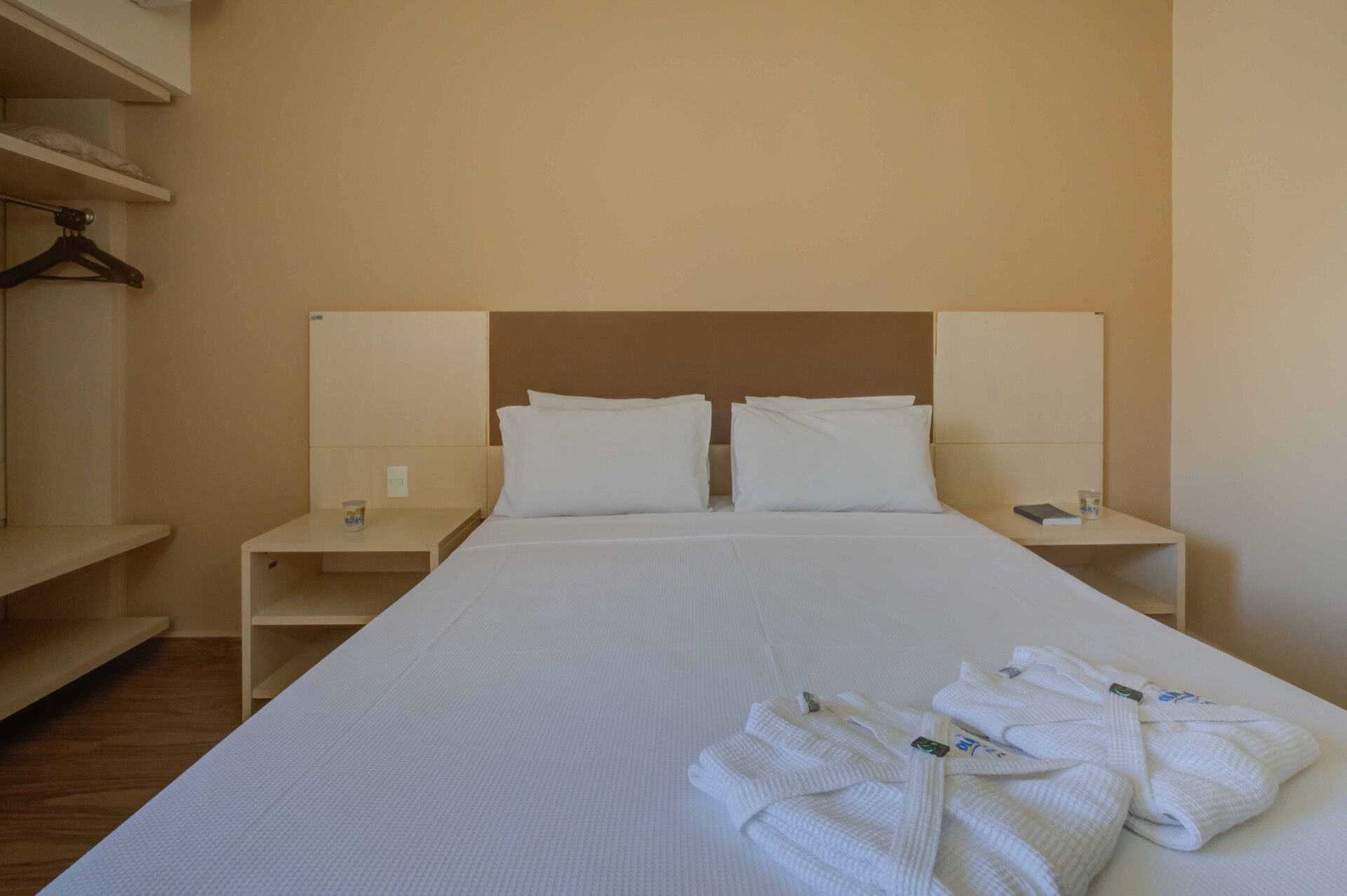 Ett hotellrum med en stor säng, två sängbord, en garderob och en handduksställning.