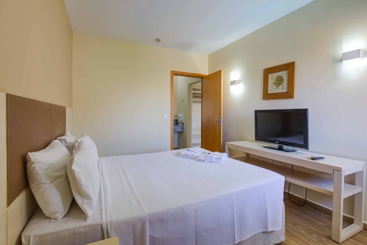 A hotel room with a bed, a TV, and a desk.