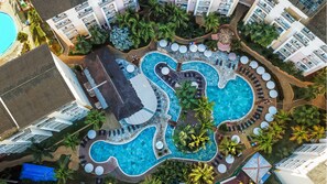 Vista aérea de un resort con varias piscinas, palmeras y una zona de playa.