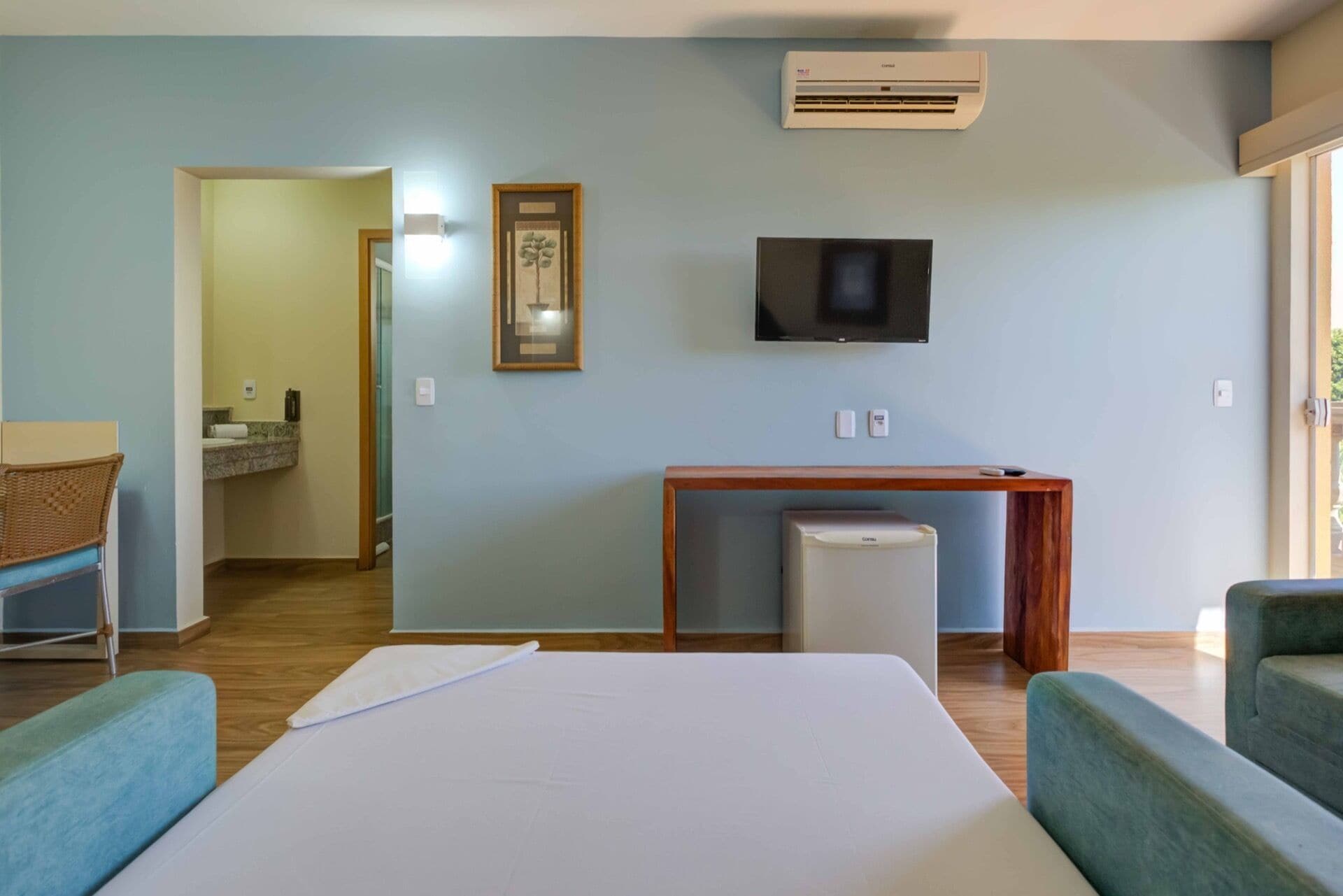 A hotel room with a bed, a TV, a small desk, and a trash bin.