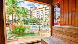 A wooden deck with a view of a pool area, including lounge chairs and umbrellas.