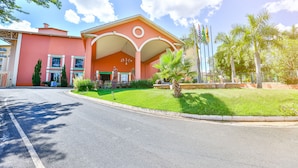 A building with a red facade, a covered entrance, and a well-maintained lawn.